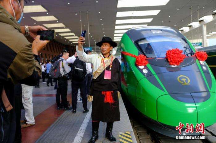 2021年6月25日，川藏铁路拉林段(拉林铁路)正式开通运营，复兴号高原内电双源动车组同步投入运营。拉林铁路全长48公里，设计时速160公里。这是西藏首条电气化铁路，也是复兴号动车组首次开进西藏。图为当日，民众在拉萨火车站复兴号车头前拍照留念。中新社记者江飞波摄