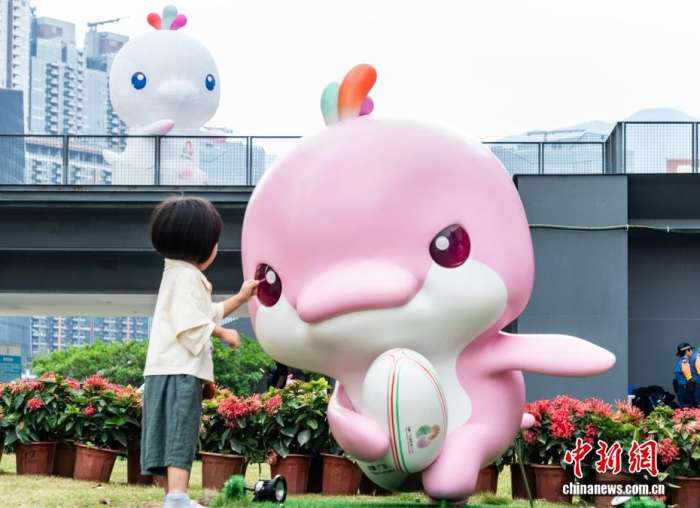 图为一名小女孩在吉祥物“乐融融”雕塑旁玩耍。中新网记者侯宇摄